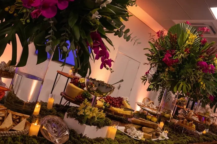 Ilha gastronômica com musgo, flores tropicais e peças de prata