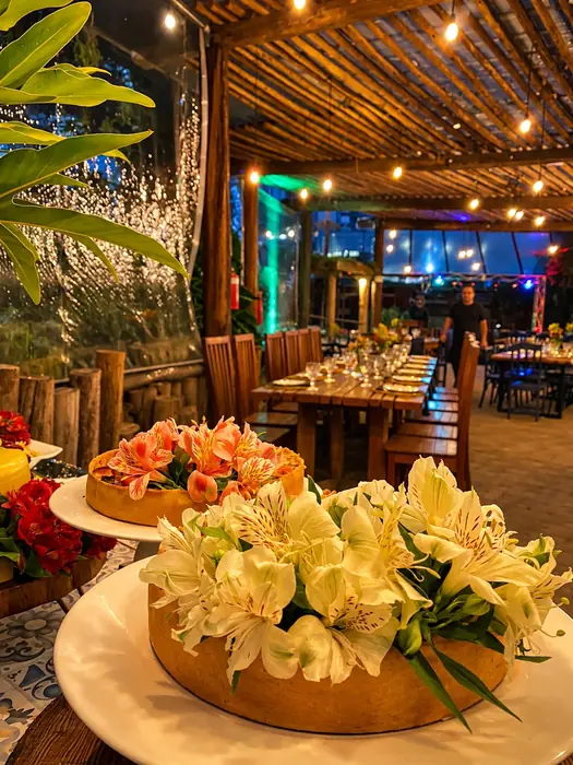 Mesa de celebração com bolo, flores e frutas sob luzes quentes